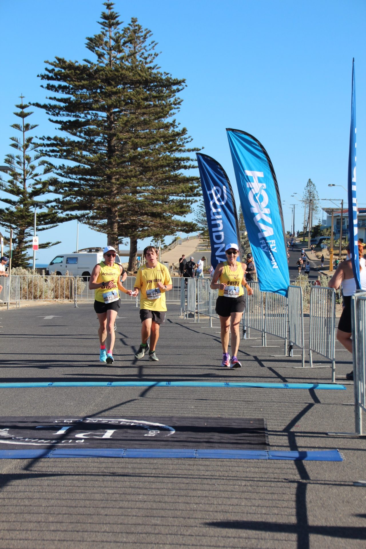 Claire, Alex, and Leonie running into the finish line at Run Moana in February 2026